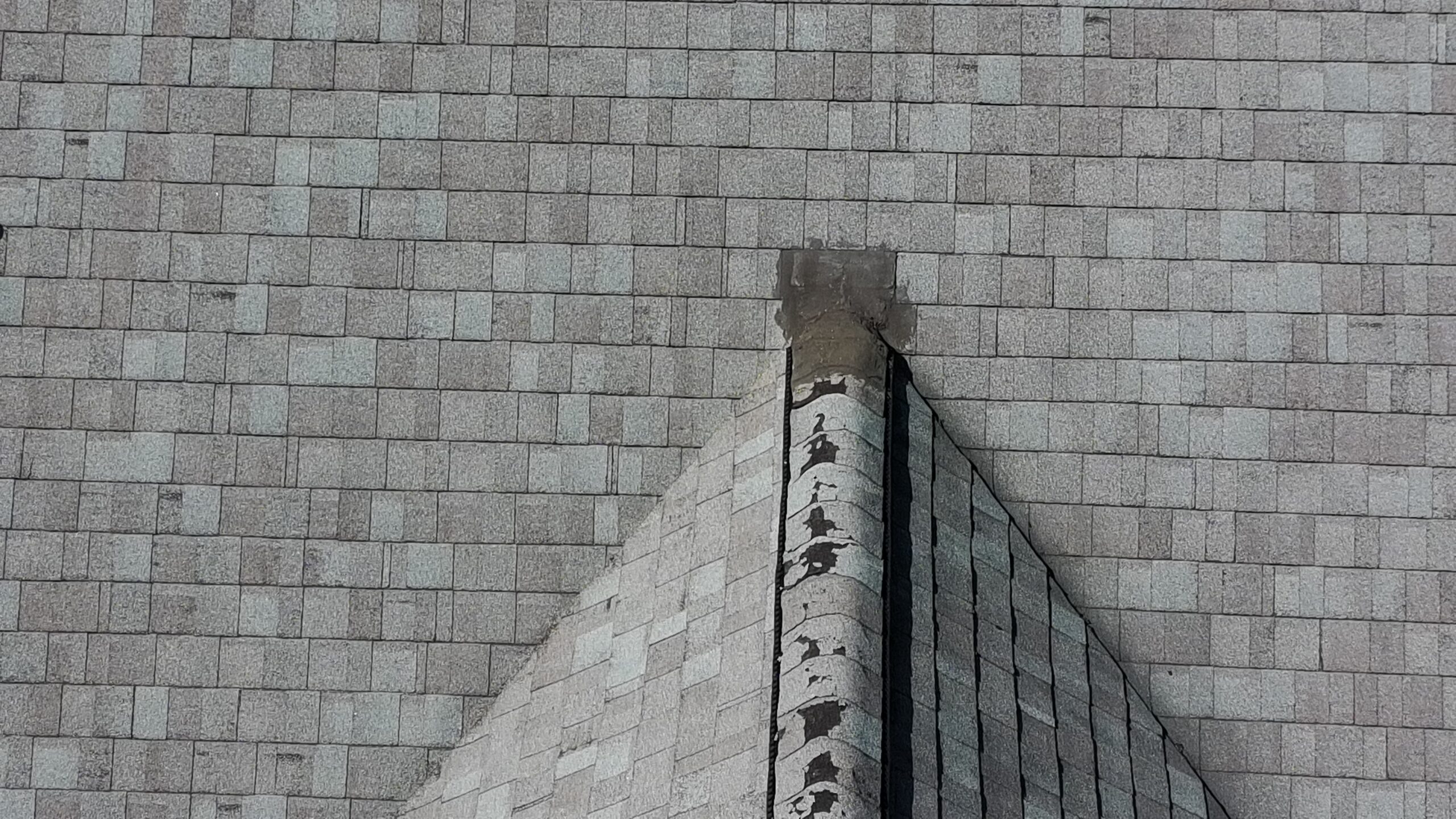 Aerial view of roof shingles and chimney flashing during a home inspection
