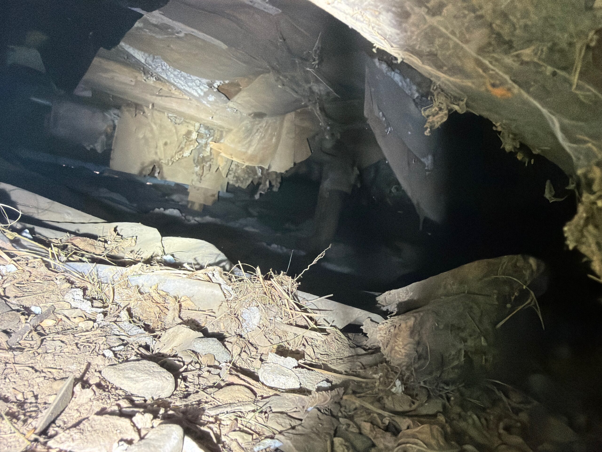 Restricted crawlspace with damaged insulation and debris observed during a home inspection